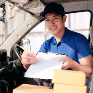 A man in a blue shirt is smiling and writing on a clipboard
