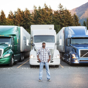 Black man truck driver near his truck parked in a parking lot at a truck stop