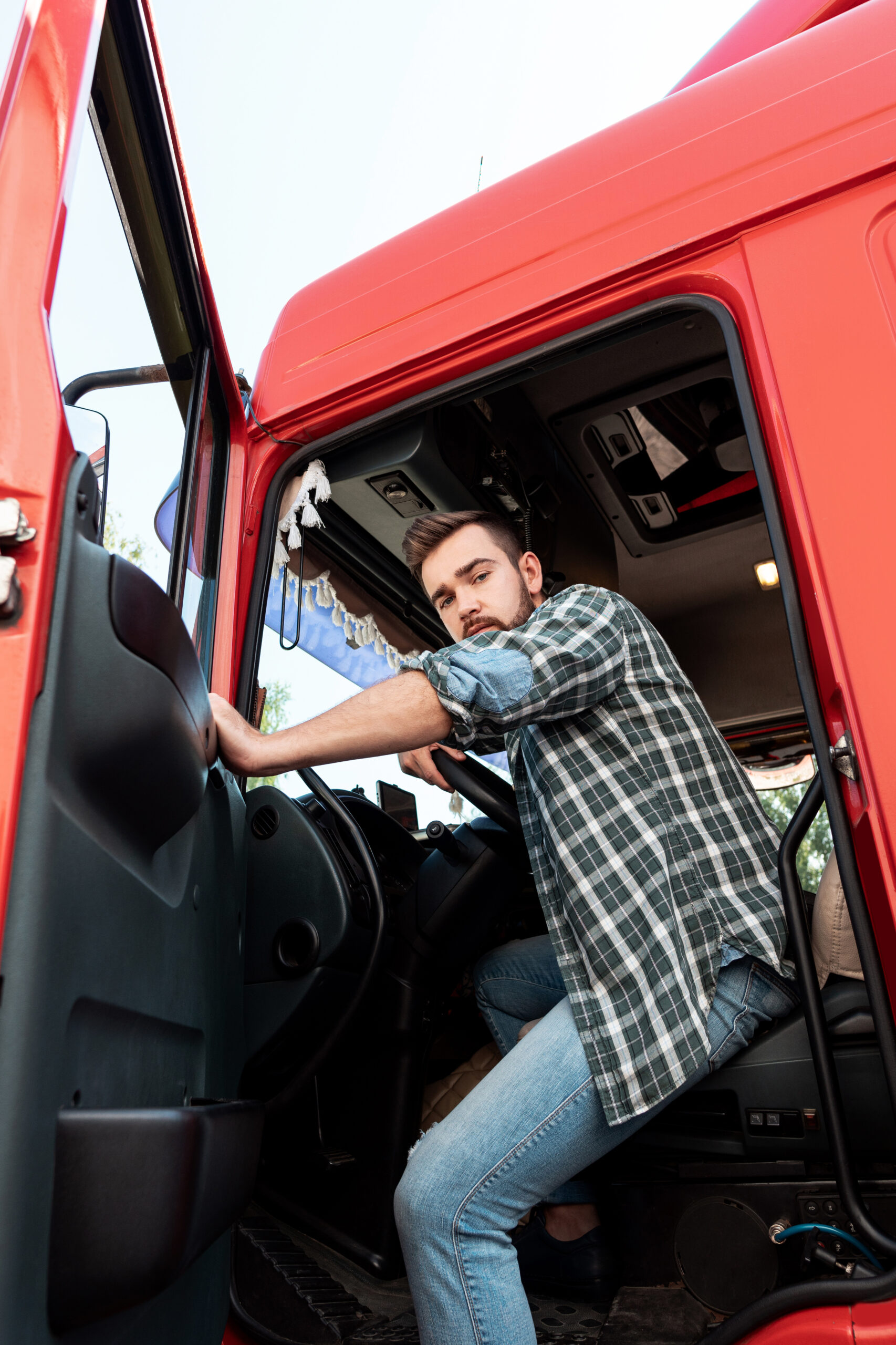 Handsome bearded truck driver inside his red cargo truck